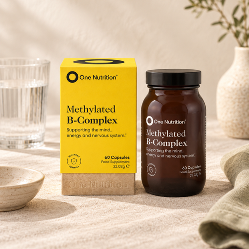 Methylated B-Complex vitamins in a glass jar and yellow packaging sitting on a neutral table in a kitchen